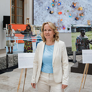 Bundesumweltministerin Steffi Lemke steht vor 3 großformatigen Fotos, die auf Staffeleien liegen.